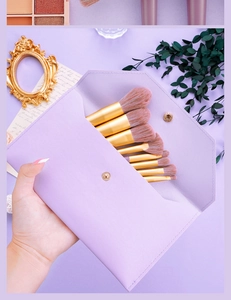 Detail showing 7 purple makeup brushes with gold tubes in a premium PU leather envelope bag