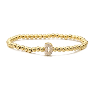 Close-up of golden beaded stretch bracelet featuring a pave zircon letter D pendant