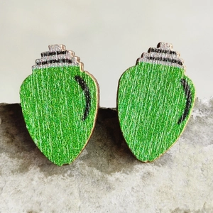 Detail of green light bulb Christmas earrings on a textured stone surface