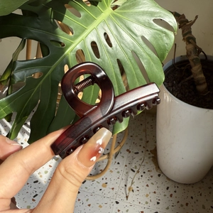 Detail of large dark brown tortoiseshell hair claw clip with glossy finish and metal spring