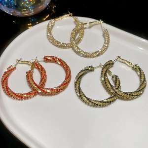 Detailed view of three pairs of sparkling rhinestone twisted hoop earrings in diverse colors