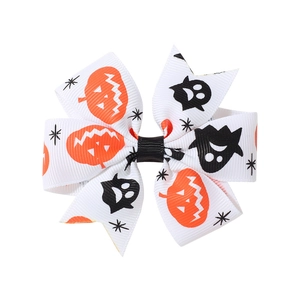 Halloween bow hair clip featuring orange pumpkin and black ghost patterns on white ribbon