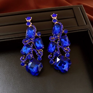 Detail of luxury long drop earrings with deep blue faceted gemstones and gold-plated alloy