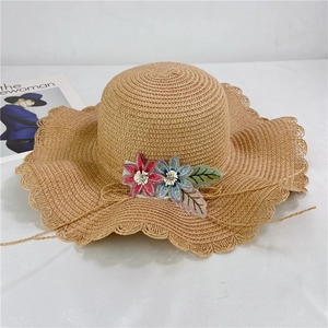 Detail of scalloped edge straw sun hat with floral embroidery and rhinestones