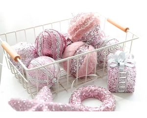 Pink glitter Christmas ornaments including balls and stars in a white metal basket
