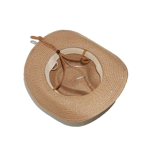Détail d'un chapeau de paille marron avec cordon réglable et texture de tissage