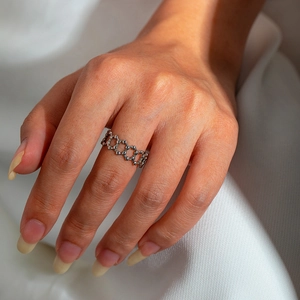 Detail shot of a silver geometric cut-out snake ring on finger with soft fabric background