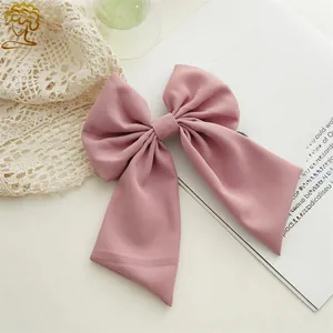 Detail shot of elegant pink bow hair clip made of silk fabric on aesthetic background