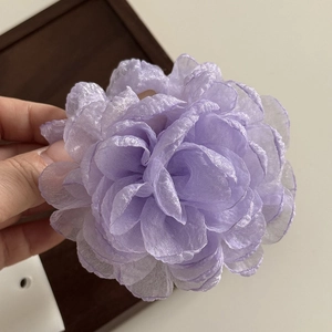 Close-up of a delicate purple tulle rose hair claw with layered shimmering fabric petals