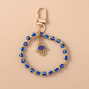 Detail of beaded evil eye keychain with gold Hamsa hand charm and metal hook