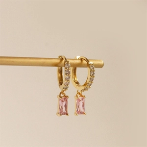 Détail macro de boucles d'oreilles en laiton doré avec zircons roses rectangulaires