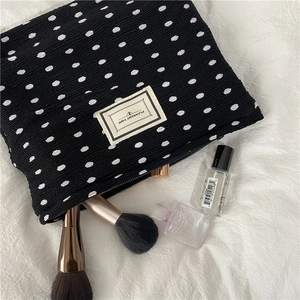 Detailed view of polka dot pleated makeup bag with Pleasant Time label on white fabric