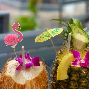Nahaufnahme von tropischen Cocktailsticks mit Flamingo und Papierschirm auf Obstgetränken