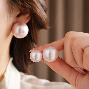 Close-up of a large round pink pearl stud earring with strong luster on the ear lobe