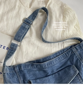Détail de la bandoulière réglable et texture du denim sur le sac bandoulière bleu
