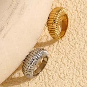 Detailed close-up of textured gold and silver croissant rings on a natural stone background