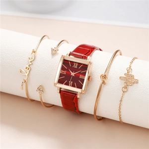 Square gold watch with red faux leather strap and four matching gold bracelets on stand