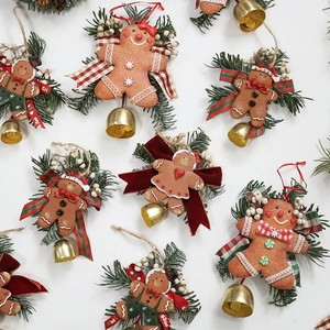 Handmade gingerbread man Christmas hanging decor with red bows, pine branches and bells