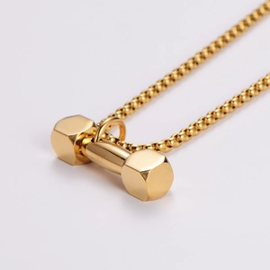Macro detail of golden dumbbell pendant necklace with sleek polished finish for men