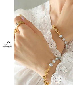 Macro detail of gold chain bracelet with grey freshwater pearls and stainless steel ring