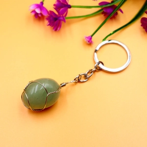 Natural green crystal stone keychain with silver wire wrap on orange background