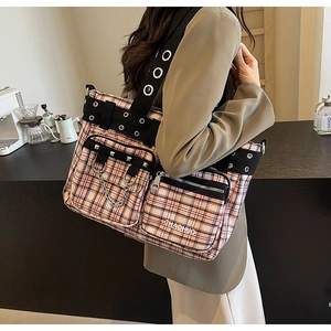 Detailed side view of pink plaid punk tote bag with studs and metal chains on shoulder