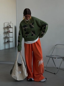 Relaxed mushroom pattern knit sweater paired with orange wide-leg trousers for women