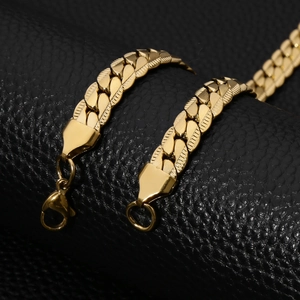Macro shot of stainless steel Cuban link chain with lobster clasp on black leather background
