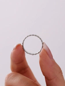 Gros plan d'une bague texturée en acier inoxydable argenté tenue entre les doigts