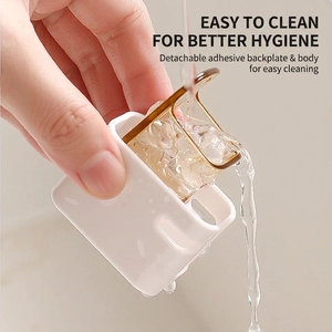 Wall-mounted toothbrush holder with white base and gold rack being washed under water