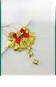 Detailed macro view of golden Christmas twin bells featuring a red bow and hanging charms.