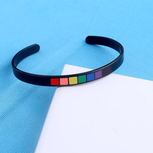 Close-up of black C-shaped cuff bracelet with vibrant rainbow color blocks on blue texture
