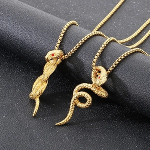 Détail de pendentifs serpent dorés avec yeux rouges sur chaînes mailles box