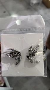 Detail view of silver liquid metal butterfly wing earrings with black stone in packaging