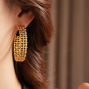 Close-up of gold hollow textured C-shaped hoop earring worn for a stylish fashion look