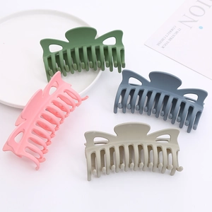 Detail view of four matte butterfly hair claws in green, pink, blue, and beige colors