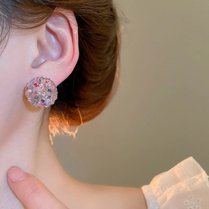 Macro close-up of a glittering pink pavé crystal ball stud earring on model ear
