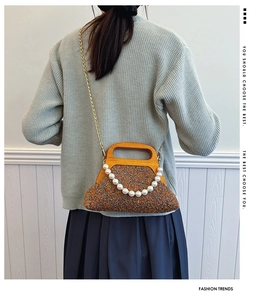 Detail of retro tweed handbag with wooden handle and decorative pearl chain strap