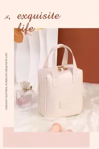 Detail der cremefarbenen PU-Leder Kosmetiktasche mit Goldreißverschlüssen und Logo