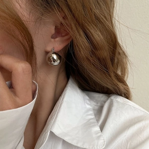 Primo piano di un orecchino sferico in argento indossato da una modella di moda