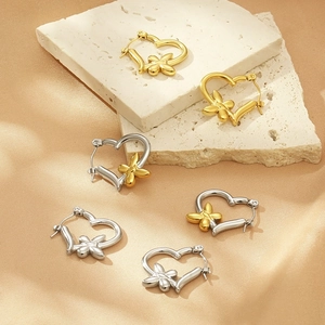 Close-up of geometric heart earrings with butterflies on textured stone and silk