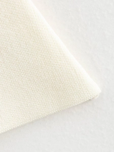 Detailed close-up of cream white knitted fabric texture with fine weave structure