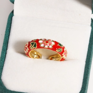 Detail of red enamel flower ring with golden finish on a white velvet jewelry box display