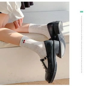 Detail of white hollow embroidery cotton socks with cherry motif and pearl black shoes