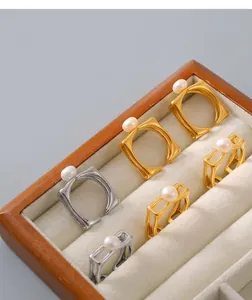 Macro shot of square pearl-set rings in gold and silver finish within a jewelry box