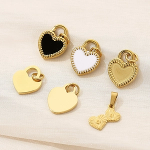 Detail view of gold, black and white enamel heart pendants on textured fabric