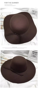 Detail view of brown wide-brim wool fedora hat with elegant wavy edge and ribbon trim