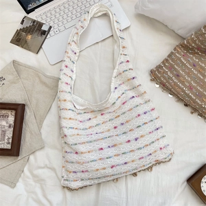 Detailed close-up of bohemian knit tote bag with colorful stripes and shell pendant