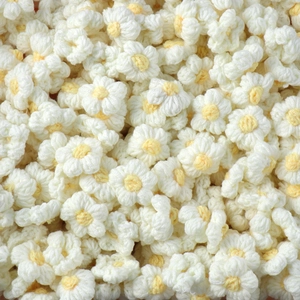 Detailed texture of bulk handmade knitted white flowers with yellow centers for keychains
