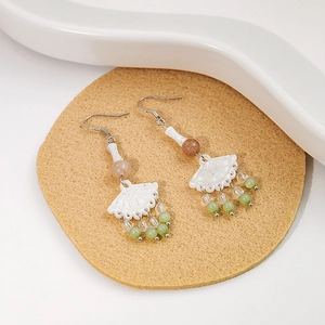 Close-up of vintage beaded earrings with white fans and green drop tassels